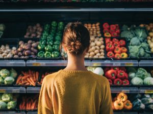 Frau steht vor einem Regal mit Gemüse