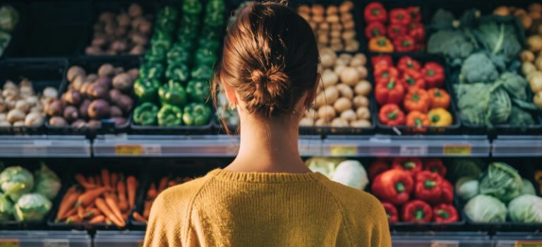 Frau steht vor einem Regal mit Gemüse